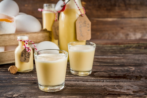 Eierlikör in Zwei Gläsern gefüllt volle Flasche dahinter.