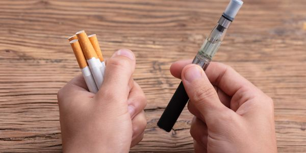 Normale Zigaretten und E-Zigarette in der Hand