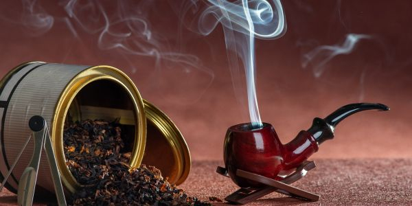 rauchende Pfeife mit offener Dose Tabak
