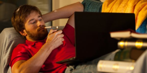 Raucher auf der Couch mit Laptop
