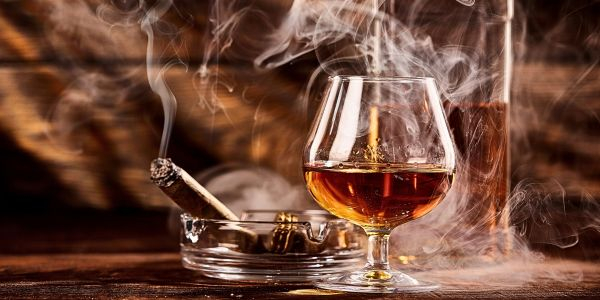 ein Glas Brandy und eine brennende Zigarre ein Glas Brandy und eine brennende Zigarre
