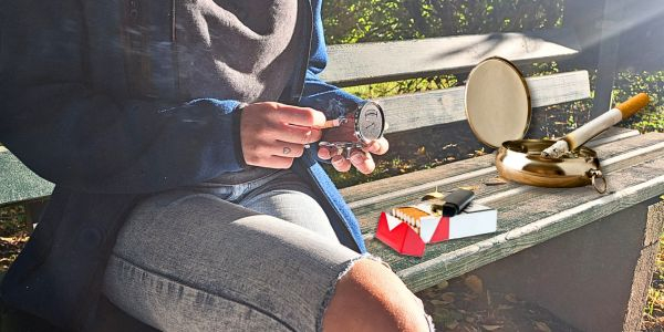 Frau beim rauchen und benutzen eines Taschenaschenbechers