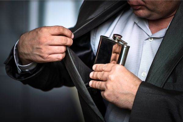 Den Flachmann in die Jackeninnentasche stecken